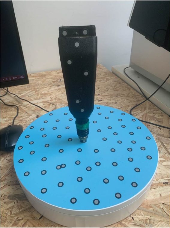Der abgebrochene Handgriff, mit Markerpunkten beklebt, auf dem Drehteller des 3D-Scanners